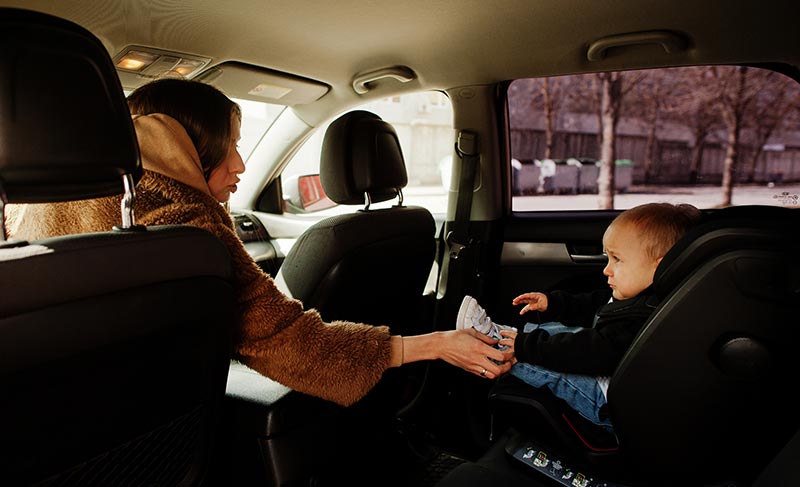Mom comforts child in car seat.